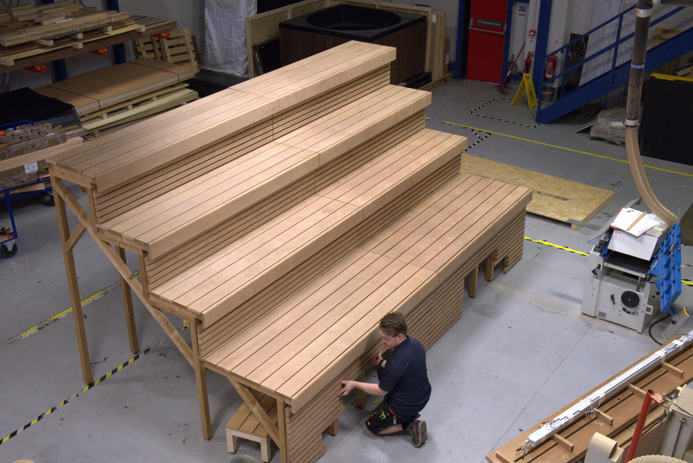Wooden panels stacked on a platform with a person working in a warehouse setting.