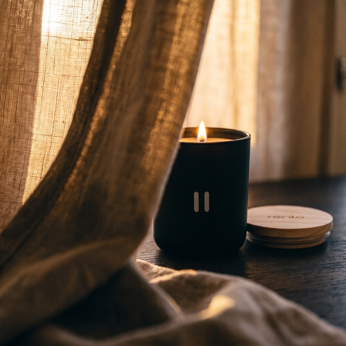 Rento Arctic Pine Scented Candle - lit behind linen curtain
