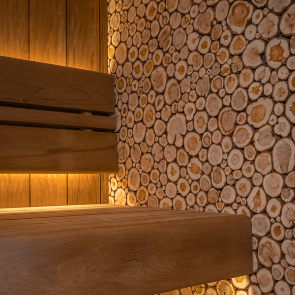 Wooden sauna bench against a wall of stacked wooden logs