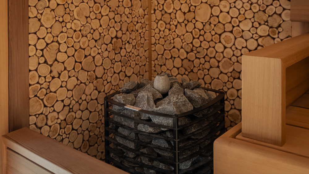 Sauna interior with wooden walls and a basket of stones.