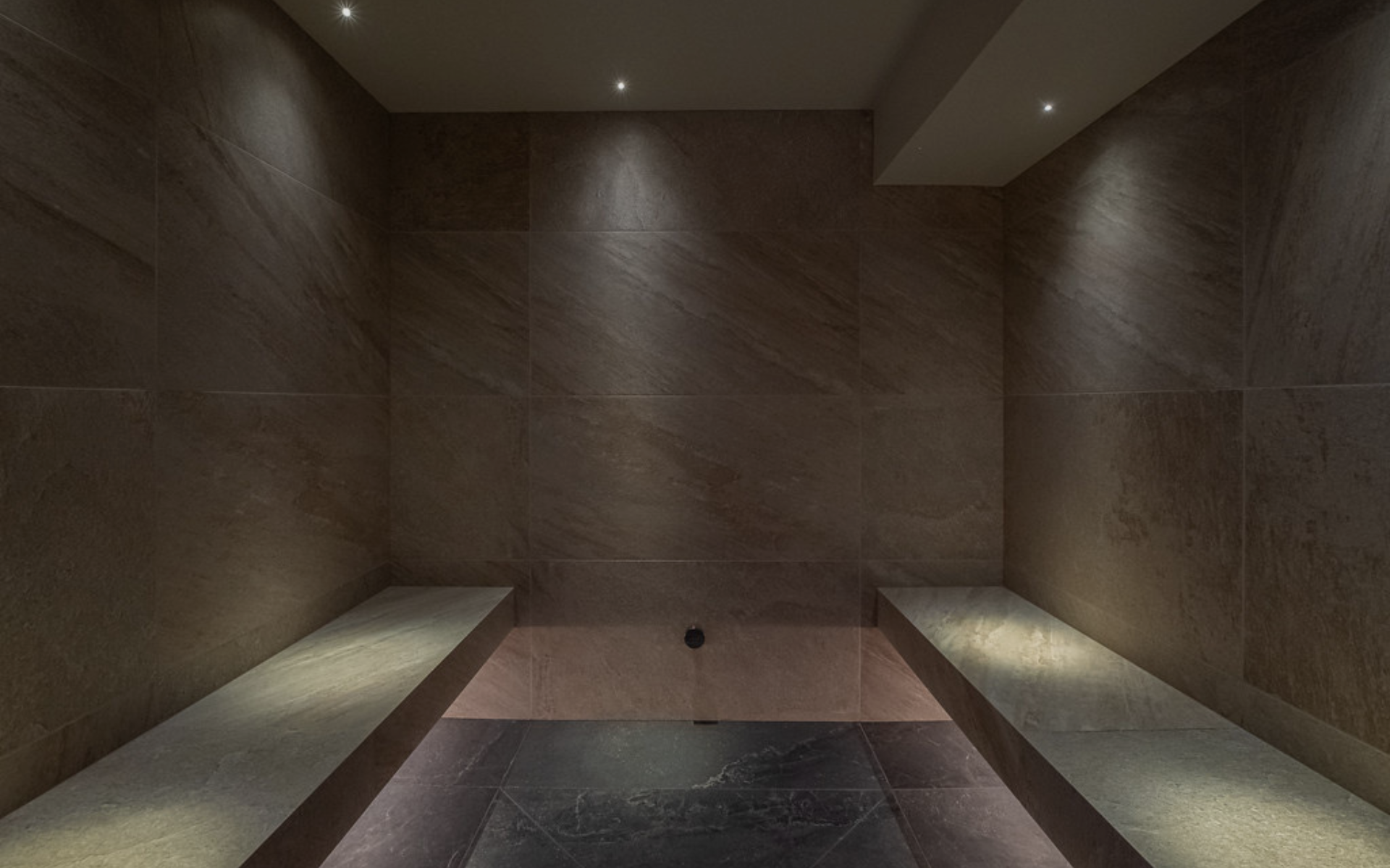 Dark room with tiled walls and a bench