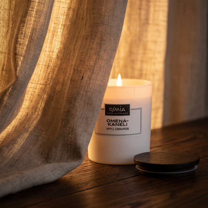 Apple-Cinnamon Scented Candle by Osmia - lit behind linen curtain